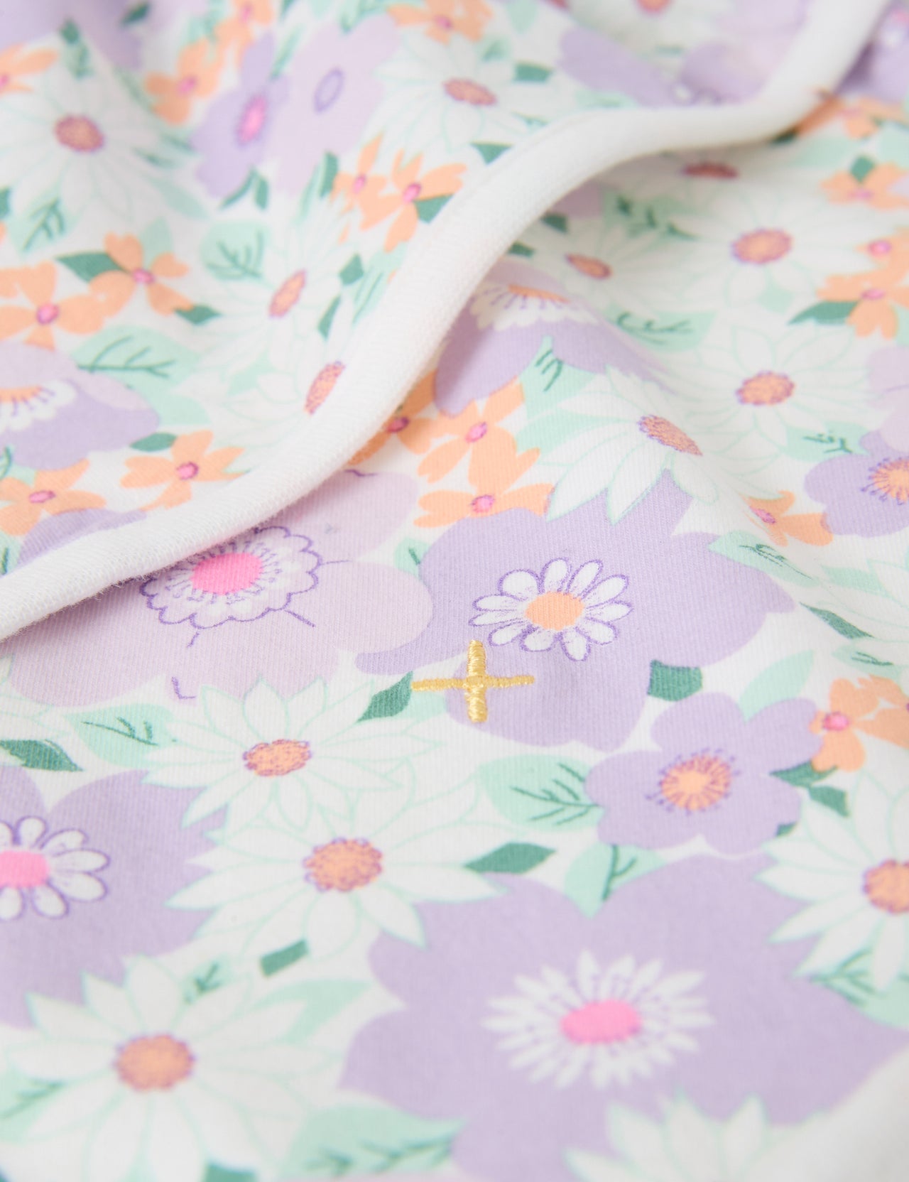 The Goldie + Ace Flora Baby Wrap in Lilac Multi pictured on a grey background. The material is soft cotton elastane. It is a babywear made for babies, toddlers and kids.