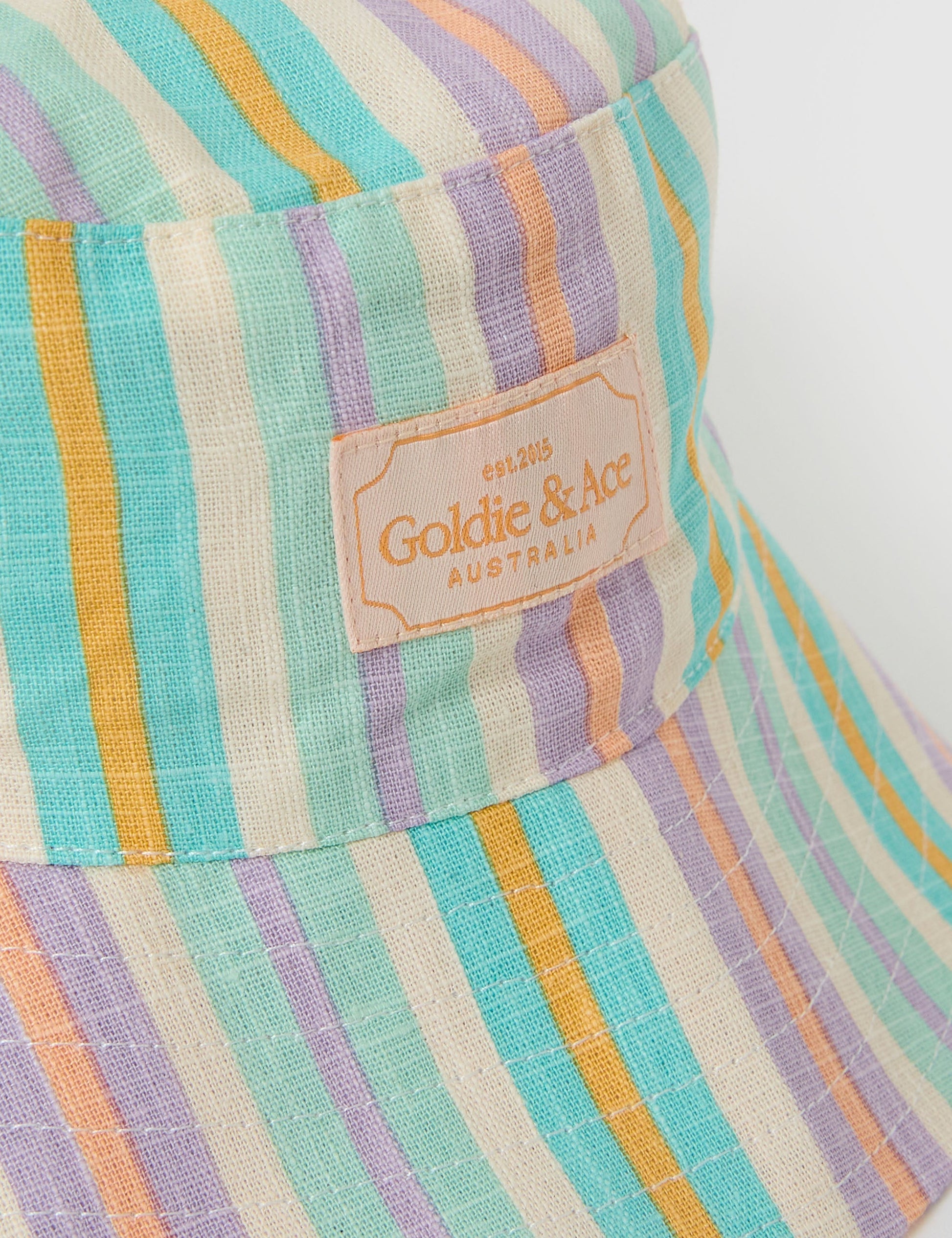 The Goldie + Ace Linen Bucket Hat in Resort Stripe pictured on a grey background. The material is linen. It is a accessory made for babies, toddlers and kids.