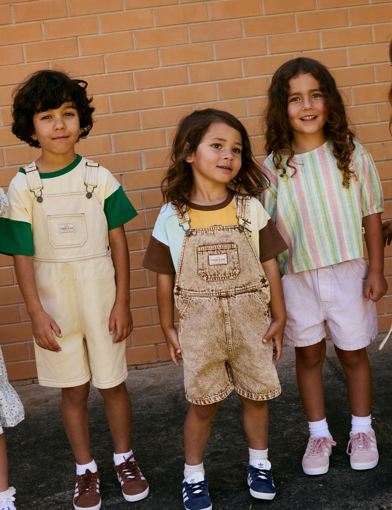 The Goldie + Ace Burton Vintage Washed Denim Overalls in Brown pictured on a grey background. The material is cotton denim. It is a overall made for babies, toddlers and kids.